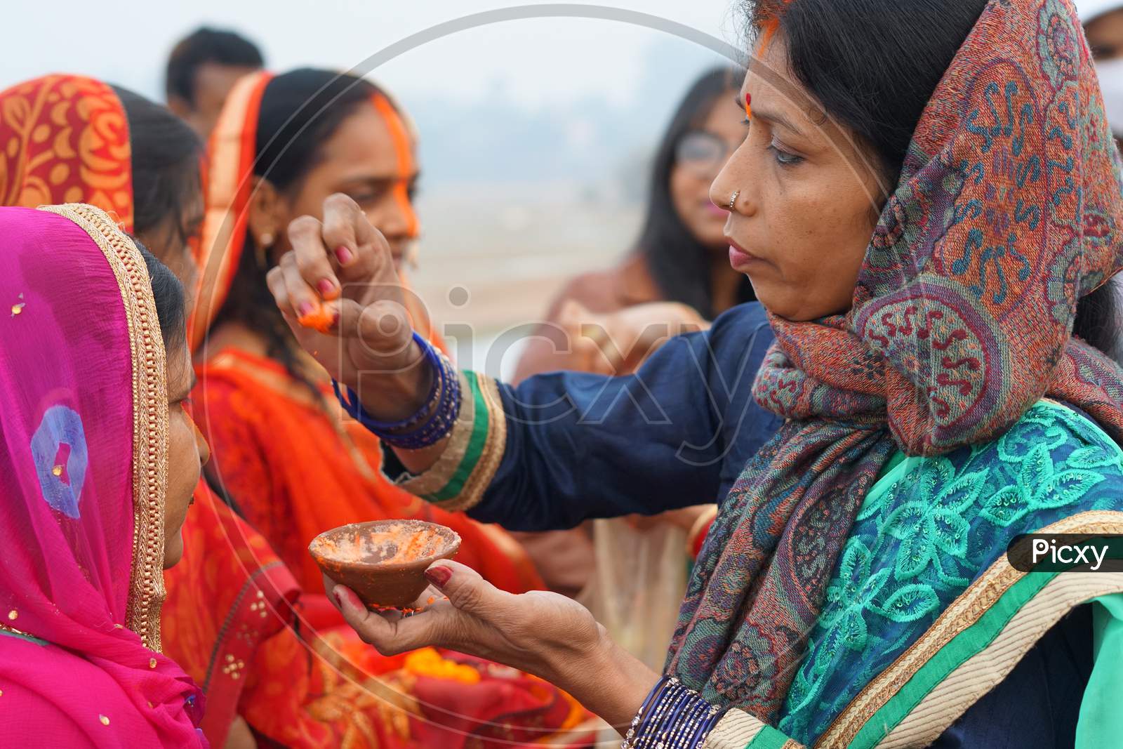 Woman applying sindoor to devotees on Chhath Puja