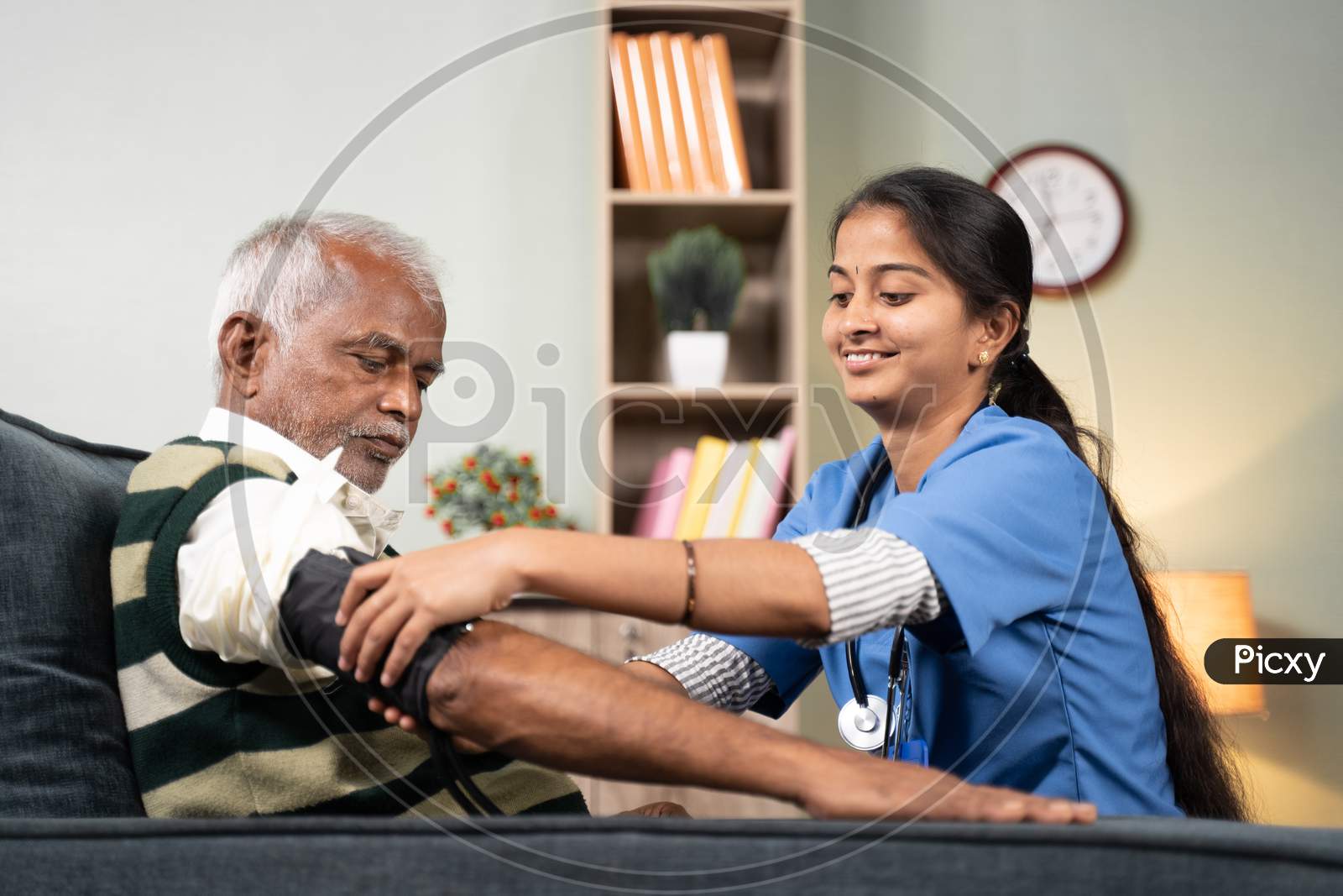 Nurse Of Doctor Busy In Setting Up Bp Or Blood Pressure Medical Equipment To Senior Man At Home Of Cheeck Up At Home - Concept Of Routine Home Help Check.