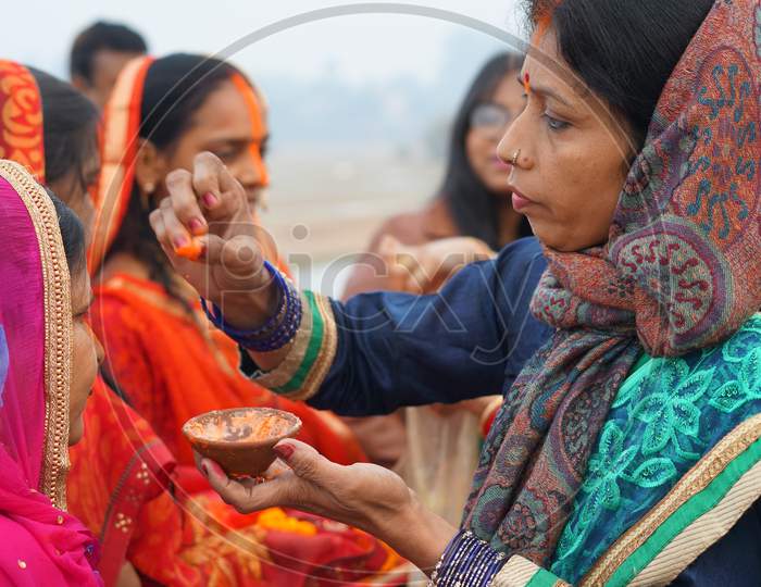 Woman applying sindoor to devotees on Chhath Puja