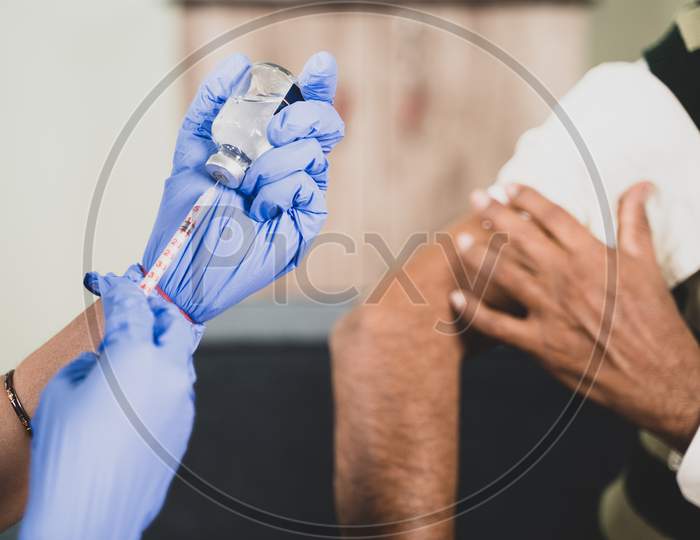 Close up Hands preparing vaccination shot to shoulder of patient - concept of coronavirus or covid-19 vaccine concept.