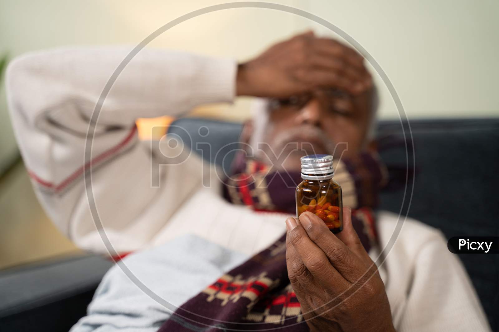 Selective focus on tablet or pills bottle, sick Old man worried about taking pills by placing hand on his head