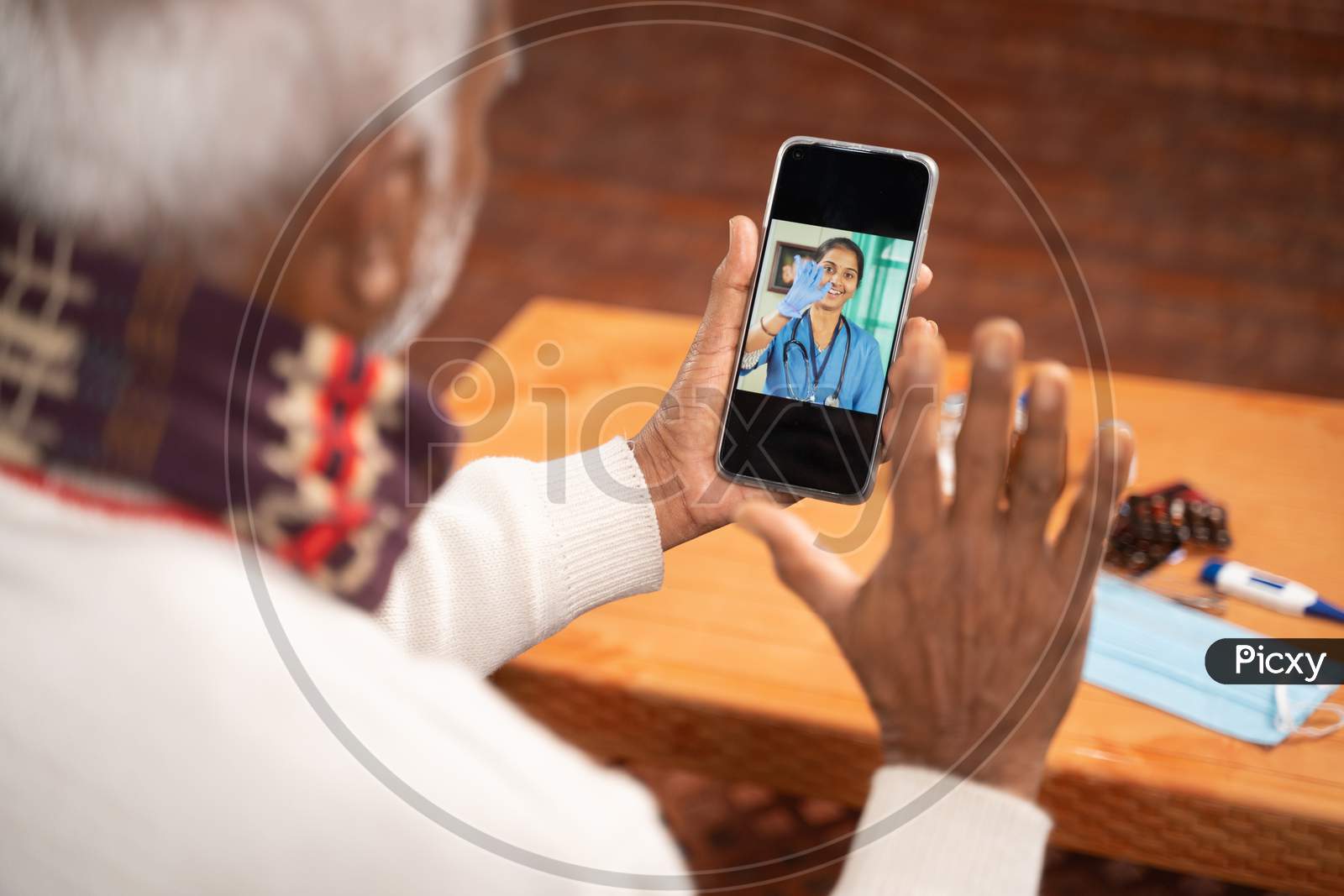 Shoulder shot of Old man on video with to doctor on mobile phone - concept of nurse Online Chat, telehealth, or tele counseling during coronavirus or covid-19 pandemic