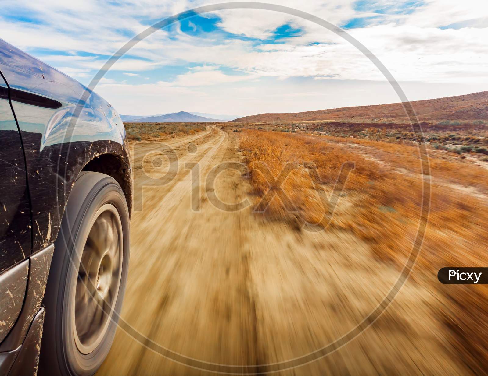 Close Up Of 4X4 Car Wheels In Motion On The Road With Deserted Landscape Background