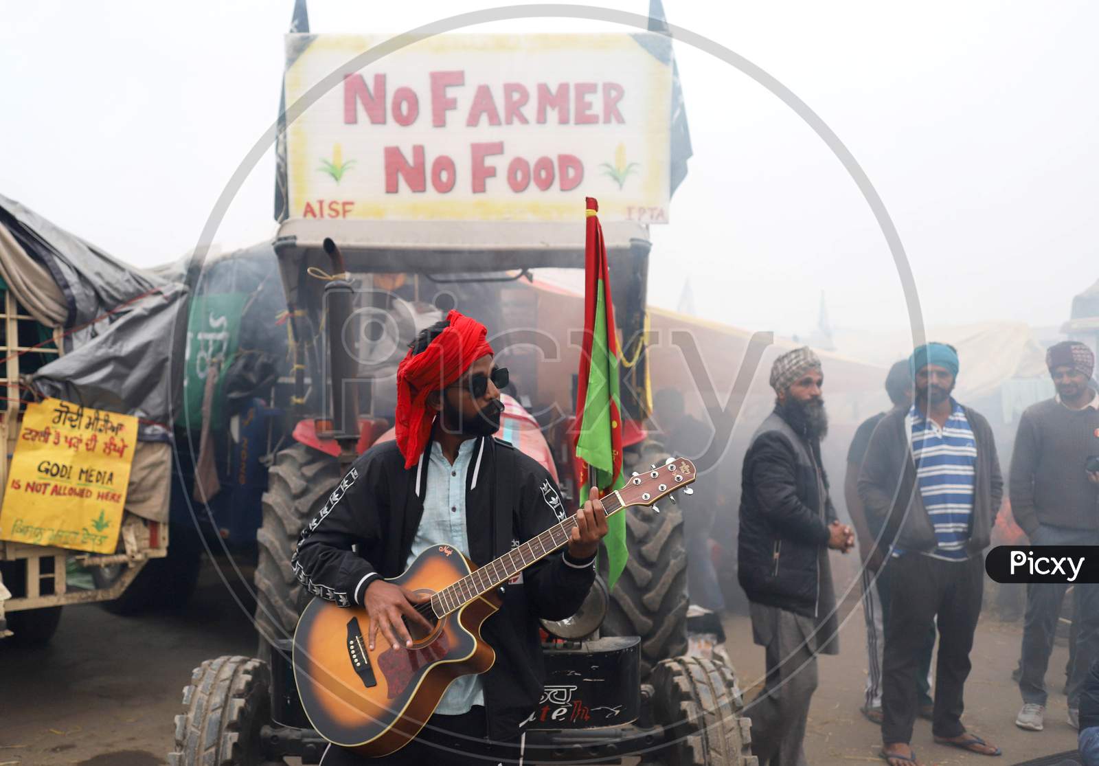 A protester plays guitar amid smoke during fumigation of an area at Singhu border where farmers are camped in an ongoing protest against the Centres new farm laws on December 11, 2020 near New Delhi, India.
