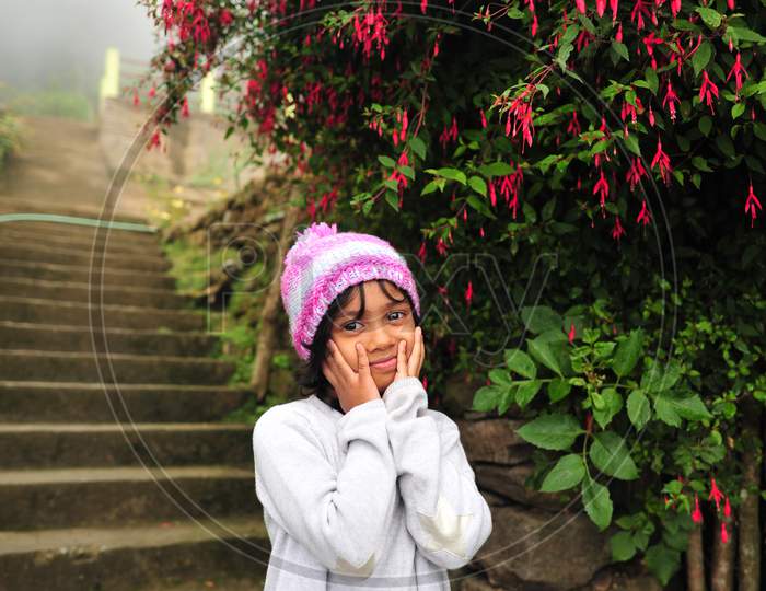 A kid in a happy state with red flower tree in the backdrop