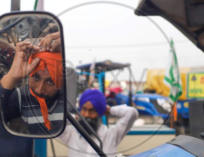 Farmers tie their turbans during an ongoing sit-in protest at Singhu border against the new farm law.