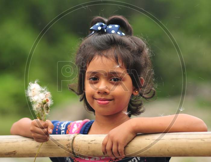 A kid girl blowing petal of dandelion and having fun