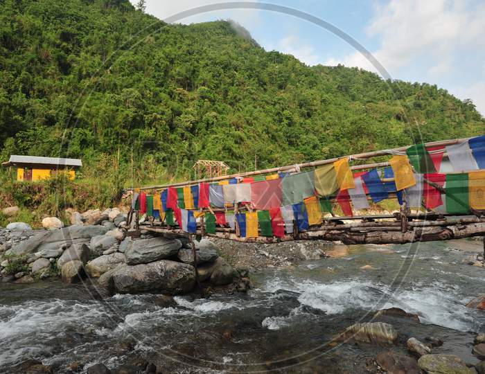 A bamboo bridge over a river with a mountain in the backdrop