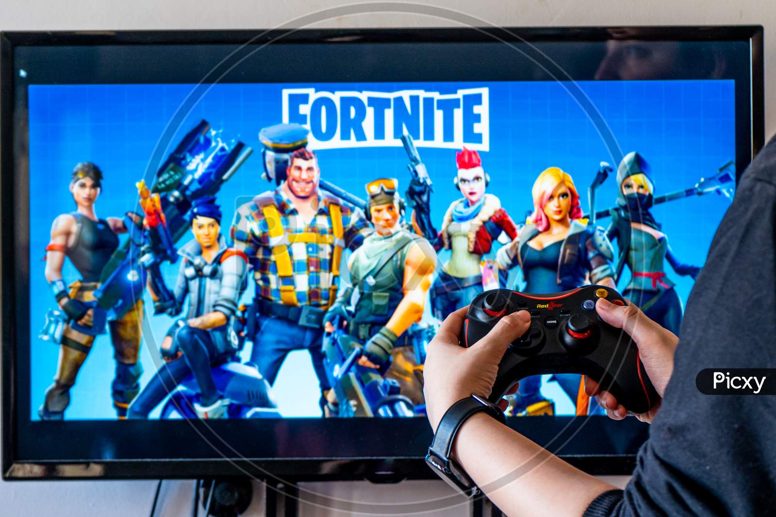 Woman Holding A Generic Controller And Playing Popular Video Game Fortnite On A Television And Pc
