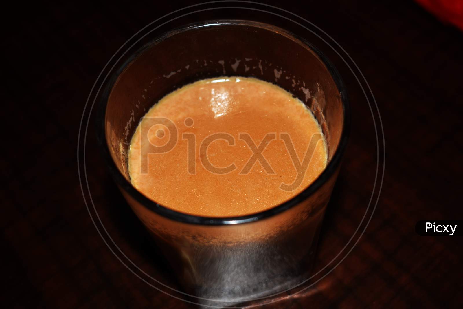 Hot Indian Orange Tea With Milk In Glass Cup On The Brown Table, Top View