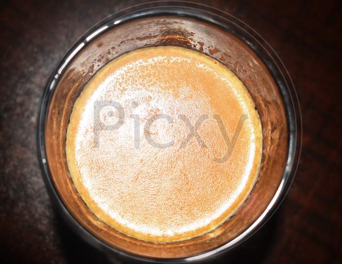 Hot Indian Orange Tea With Milk In Glass Cup On The Brown Table, Top View