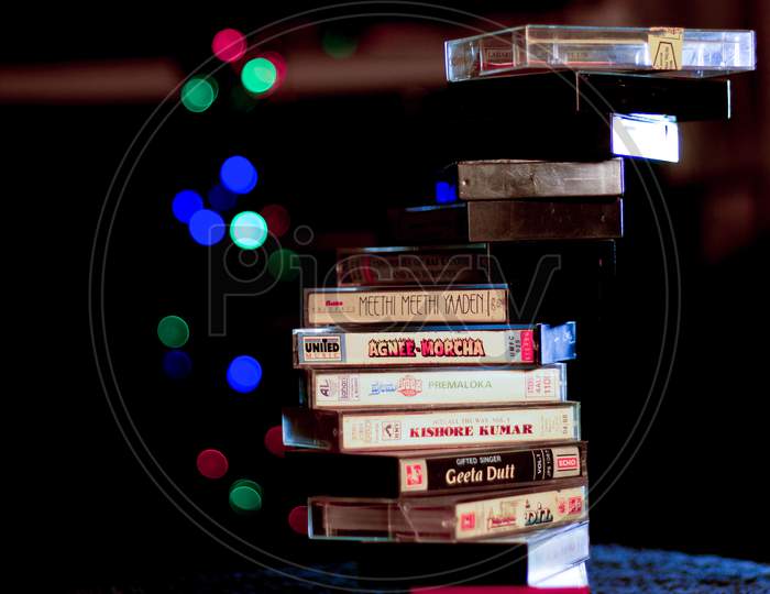 An Elegant collection of Magnetic Audio tapes arranged aesthetically  against a Bokeh background in a dark room.