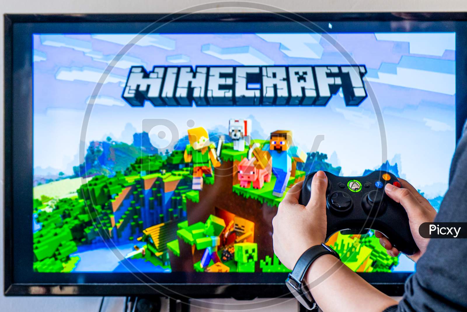 Woman Holding A Xbox Controller And Playing Popular Video Game Minecraft On A Television And Pc