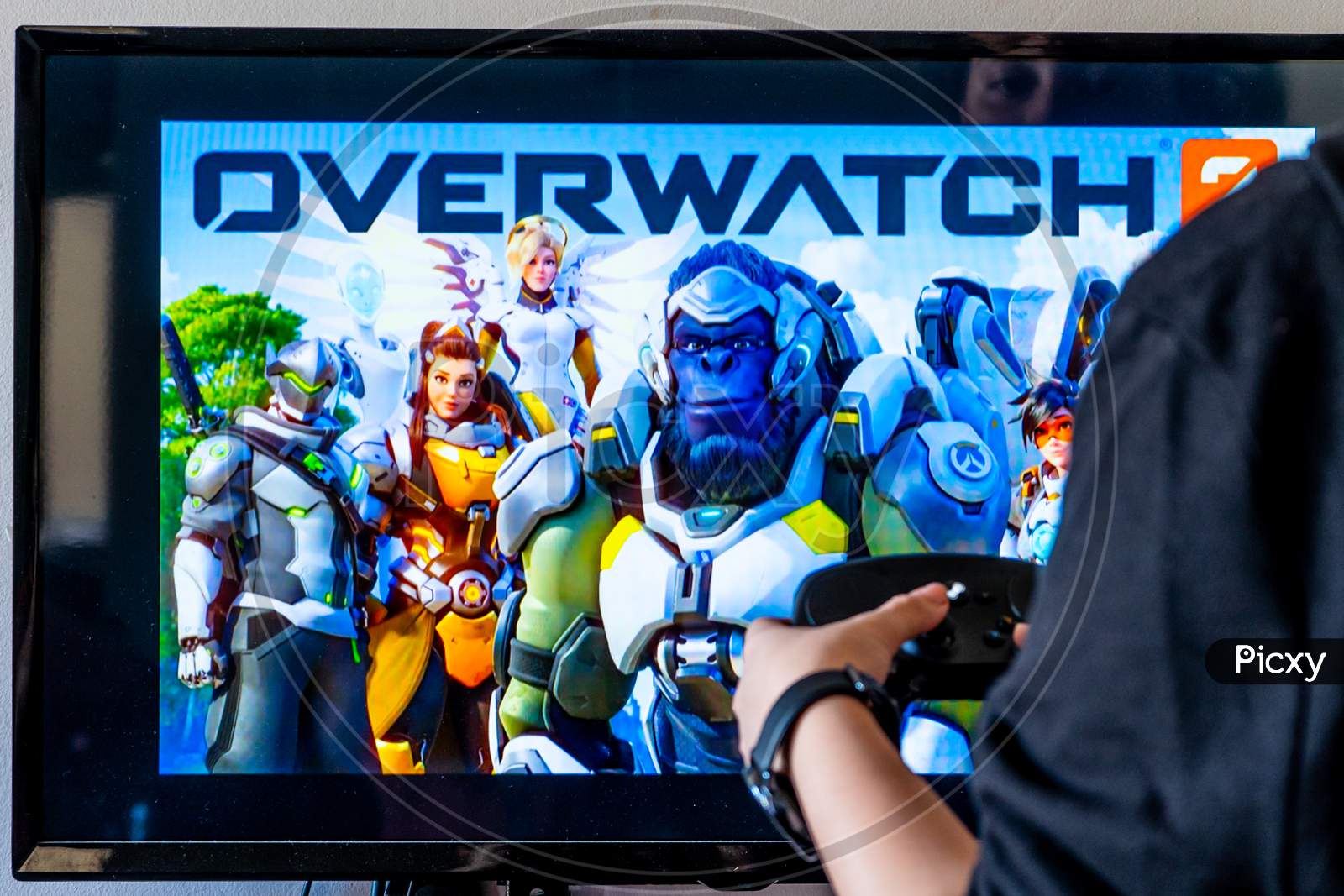 Woman Holding A Steam Controller And Playing Popular Video Game Overwatch On A Television And Pc