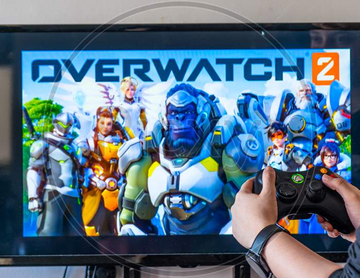 Woman Holding A Xbox Controller And Playing Popular Video Game Overwatch On A Television And Pc