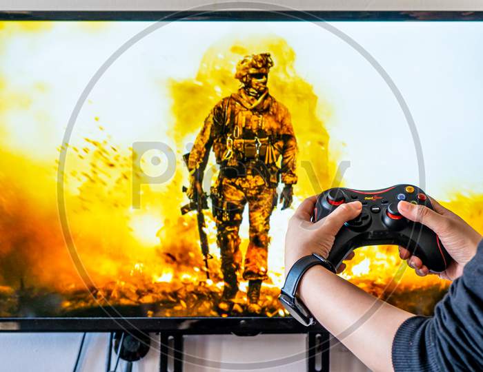 Woman Holding A Generic Controller And Playing Popular Video Game Call Of Duty On A Television And Pc