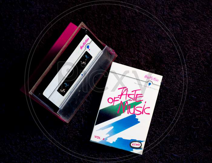 A Pretty picture of a Music Audio Cassette tape with its case against the Black background with a natural light source.