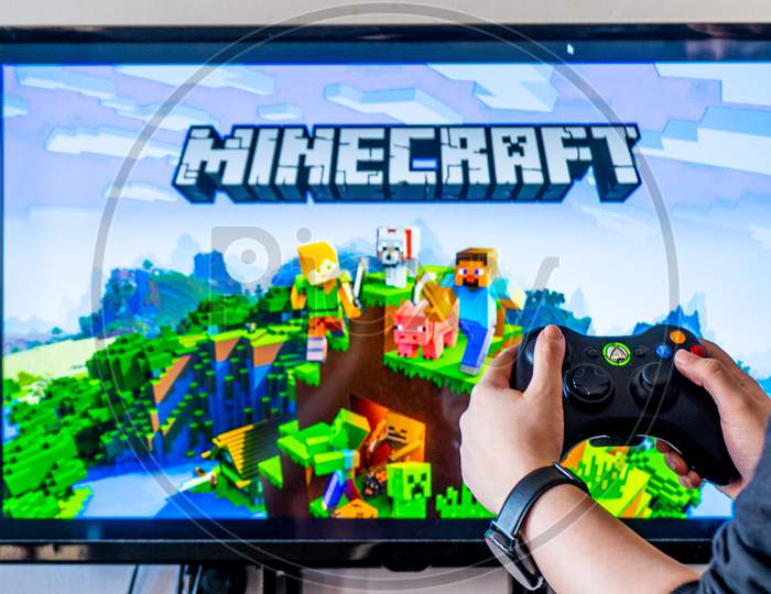 Woman Holding A Xbox Controller And Playing Popular Video Game Minecraft On A Television And Pc