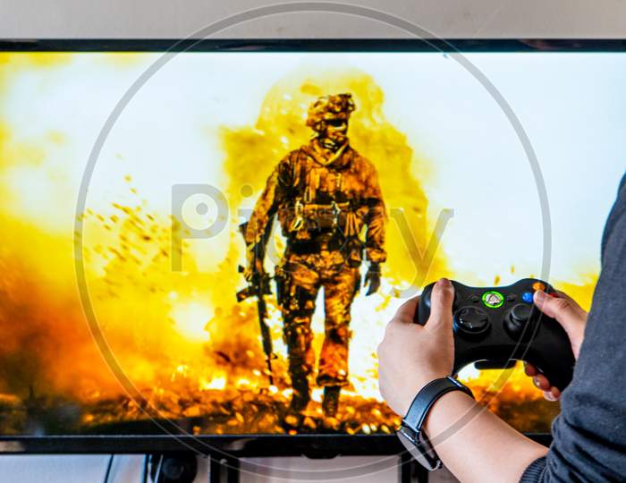 Woman Holding A Xbox Controller And Playing Popular Video Game Call Of Dutyon A Television And Pc
