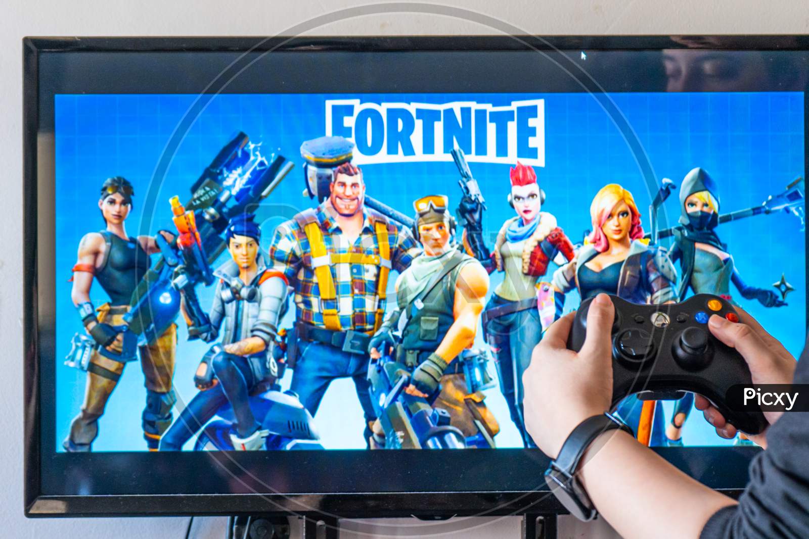 Woman Holding A Xbox Controller And Playing Popular Video Game Fortnite On A Television And Pc