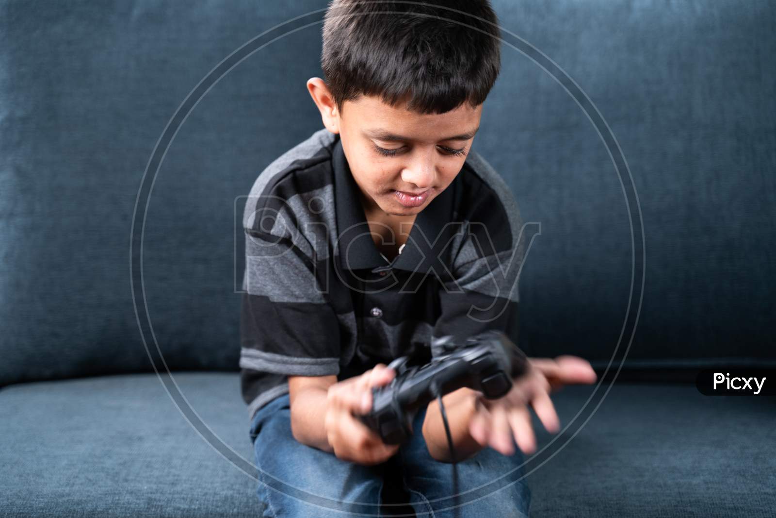Selective Focus On Kid, Kid Hitting The Gamepad Or Joystick Due To Not Working Properly While Playing Videogame At Home On Sofa.