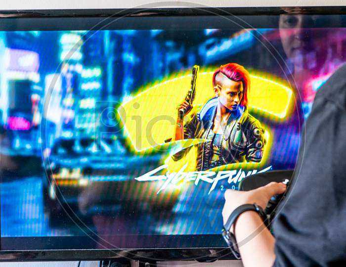 Woman Holding A Steam Controller And Playing Popular Video Game Cyberpunk 2077 On A Television And Pc