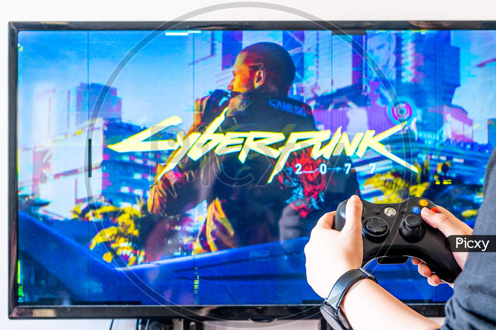 Woman Holding A Xbox Controller And Playing Popular Video Game Cyberpunk 2077 On A Television And Pc