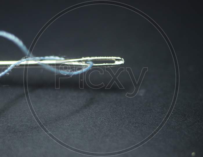 Small Needle With Thread In The Eyelet, Isolated Over The Black Background.