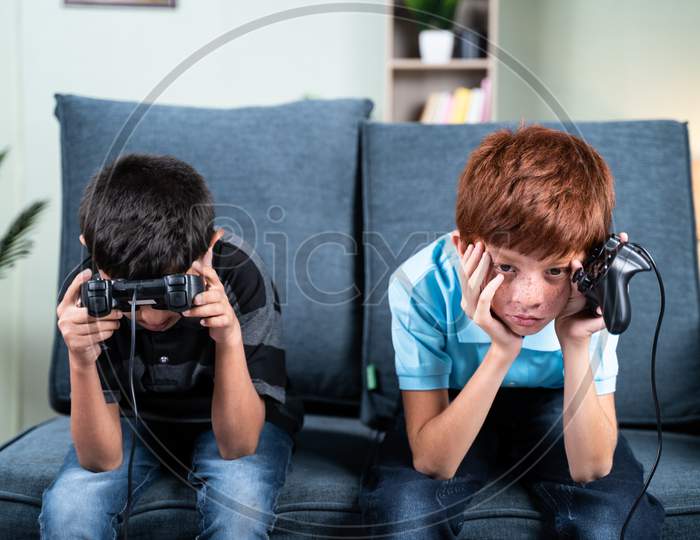 Young Kids Feeling Sad Due To Lost In Videogame While Playing At Home On Sofa - Concept Of Frustration Or Sadness Due To Failure In Game During Childhood.