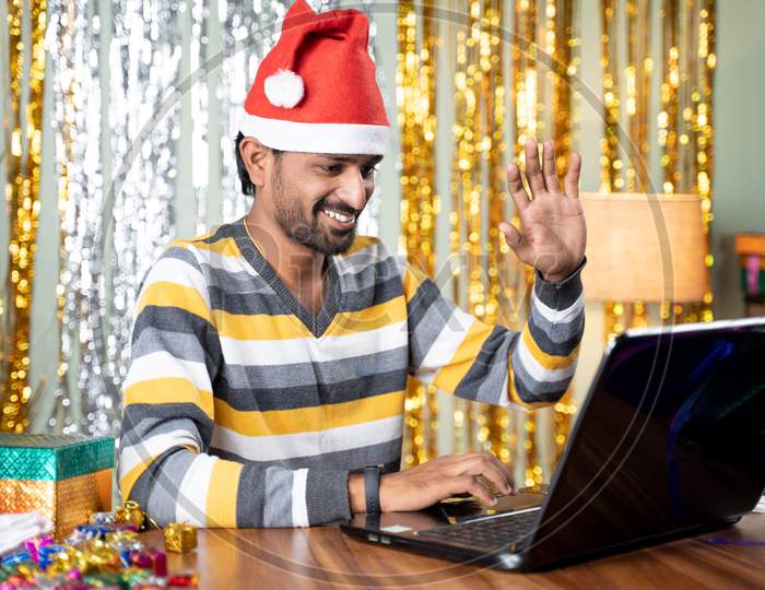 Young Man On Video Call In Laptop During Christmas Or New Year Eve With Decorated Background - Concept Of Distance Holiday Or Festive Celebration Due To Coronavirus Or Covid-19 Pandemic.