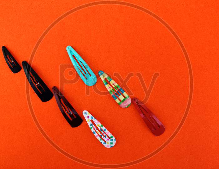 Various Colored Trendy Hair Clips Isolated On Orange Background