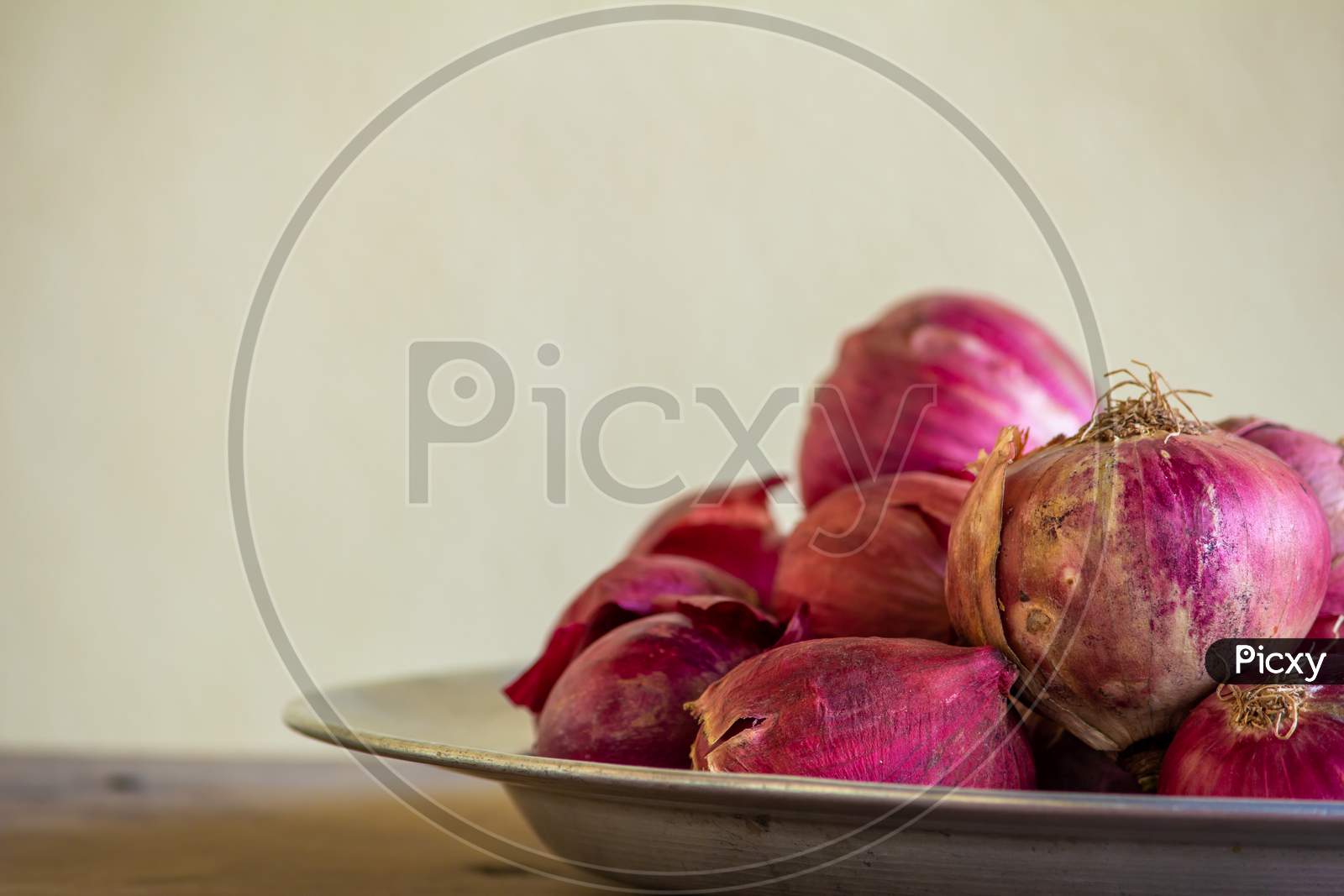 View Of Red Onions In A Plate Over A Wooden Table