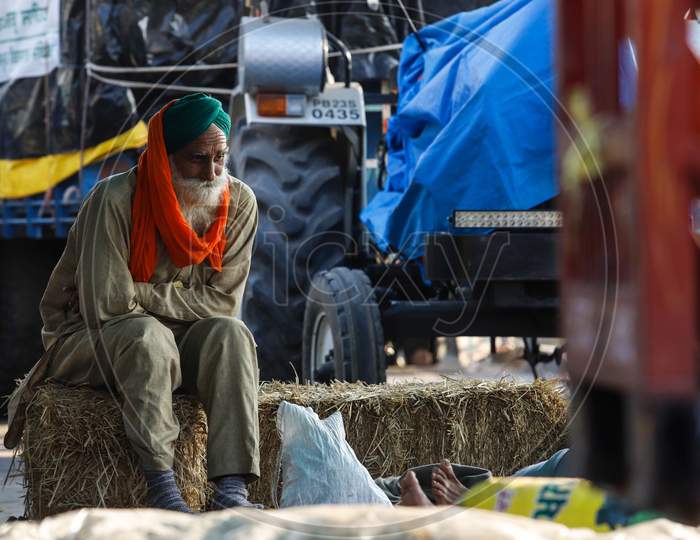 A Farmer Sits Over A Bundle Of Hay During  The Ongoing Sit-In Protest At Singhu Border Against New Farm Laws On December 13, 2020 Near New Delhi, India. Thousands Of Farmers Are Protesting On Various Borders Of The National Capital Since November 26.