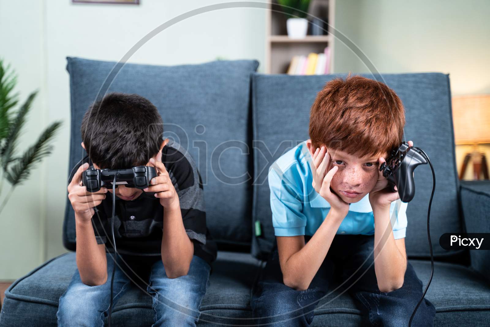 Young Kids Feeling Sad Due To Lost In Videogame While Playing At Home On Sofa - Concept Of Frustration Or Sadness Due To Failure In Game During Childhood.