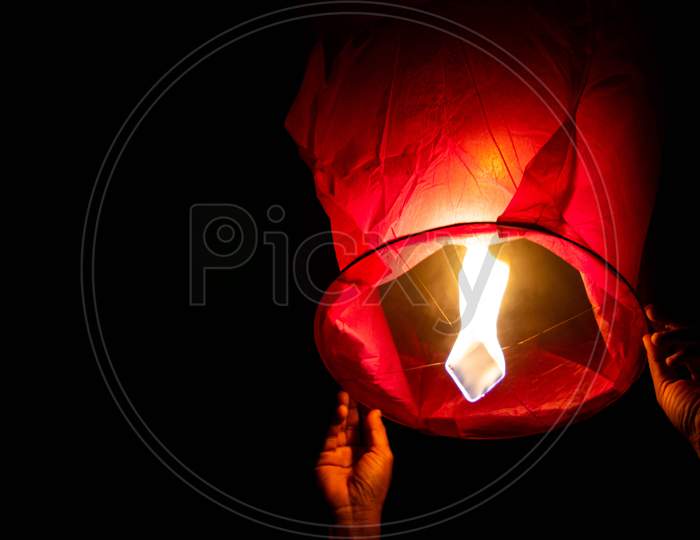 Person Holding A Red Sky Lantern With The Flames Showing Clearly