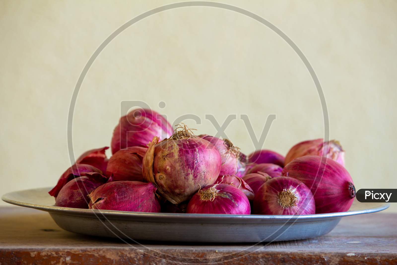 View Of Red Onions In A Plate Over A Wooden Table