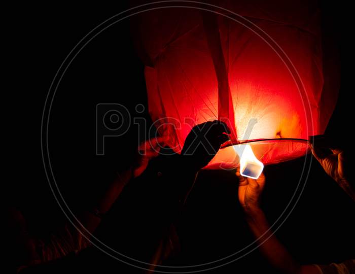 Person Holding A Red Sky Lantern With The Flames Showing Clearly