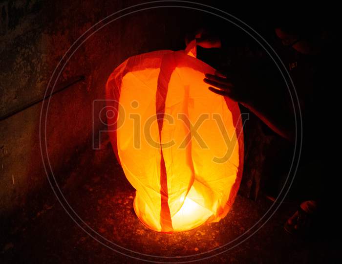 Red Sky Lantern With The Flames Showing Clearly Held On The Ground