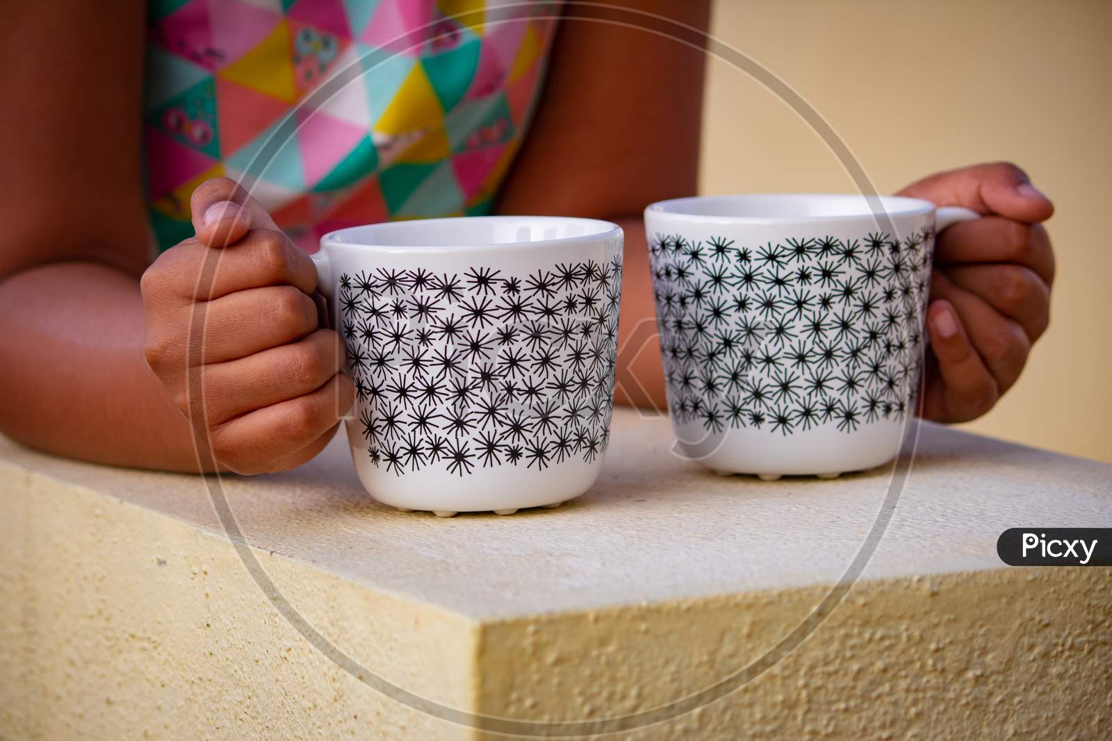 View Of Young Girl Holding Coffee Mugs In Both Her Hands