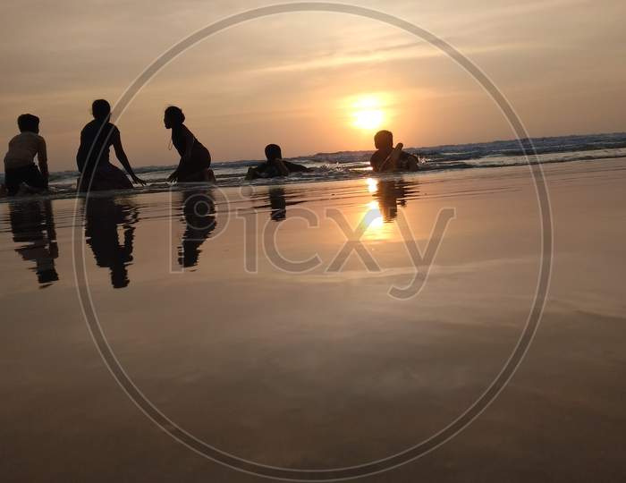 Kids playing at beach during sunset