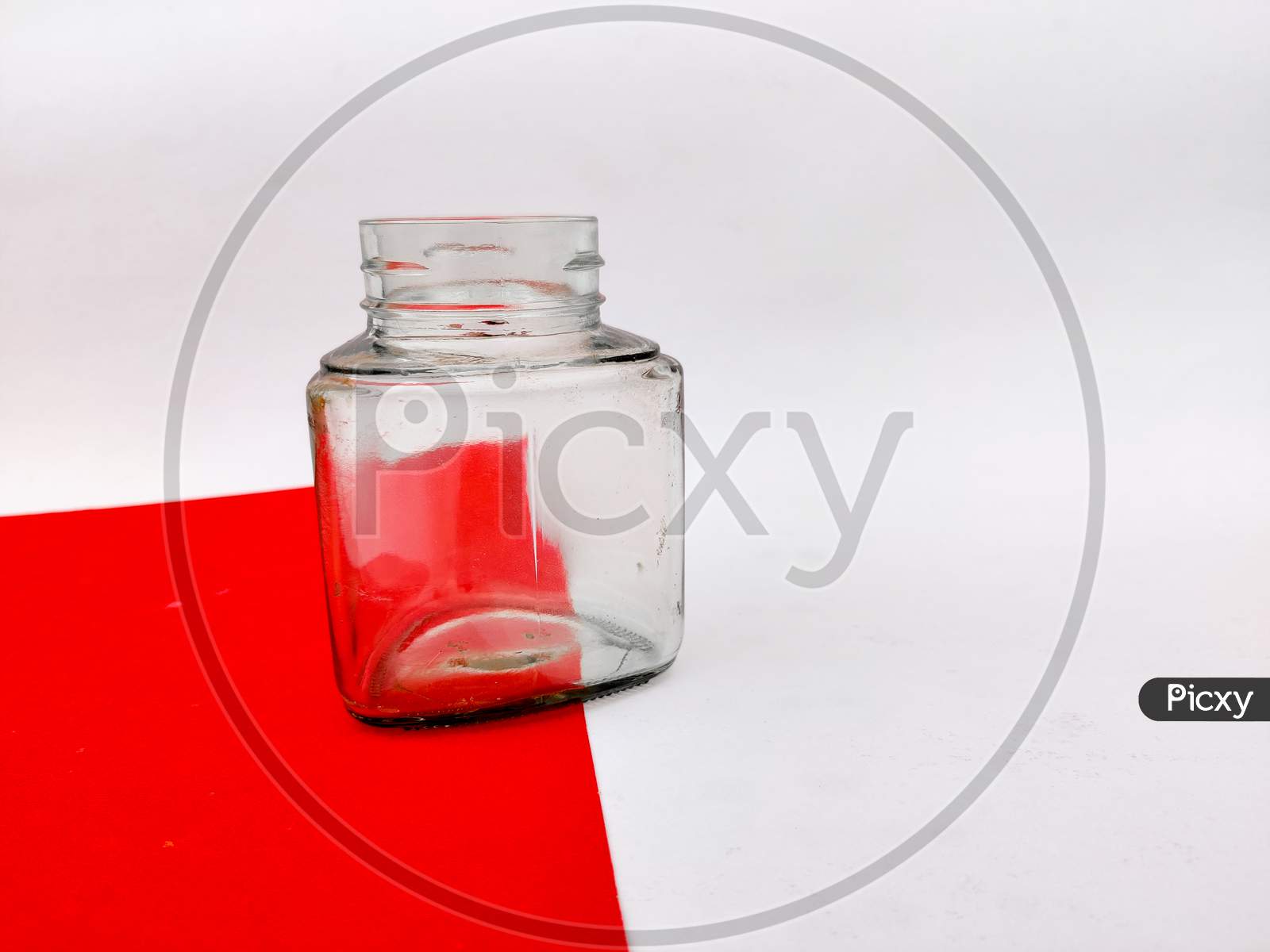 Empty Glass Jar On Red Sheet. Isolated On White Background.