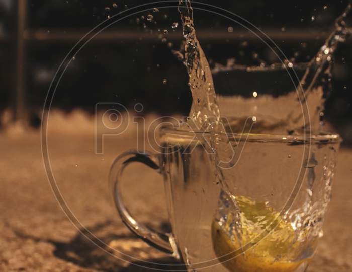 Lemon dropped into glass of water, water splash out.