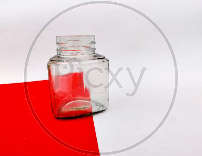 Empty Glass Jar On Red Sheet. Isolated On White Background.