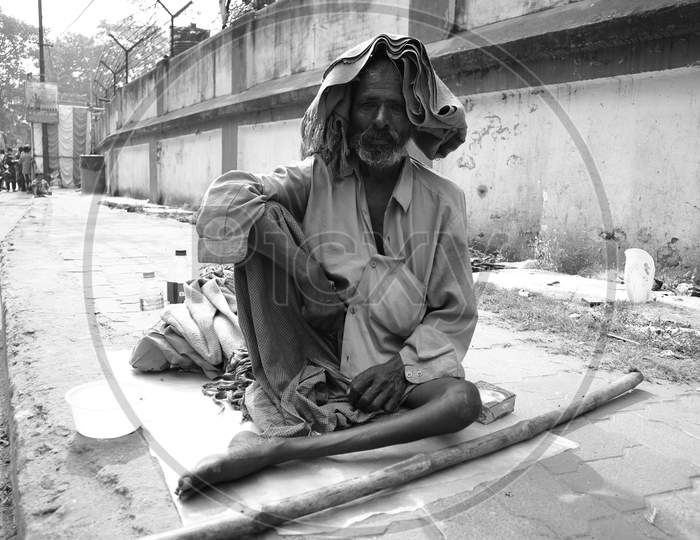 A old homeless man sitting on the side walk