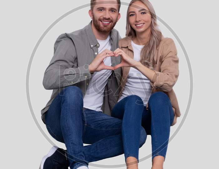 Couple Sitting On Floor Showing Heart Sign. Couple Showing Love Sign. Relationship, Family, Lovers, Friends Concept