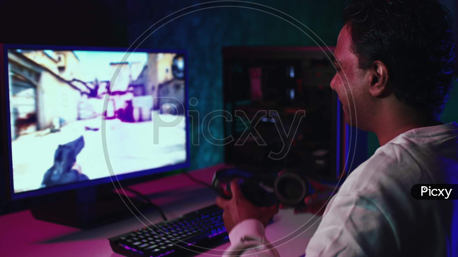 Indian Man Starts To Play Pc Game. Man Puts On Headphones And Plays Shooting Game. Gamer At Home Playing Games. Indian Man Playing Games. Shot On Red