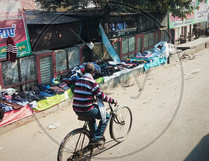 Indian man riding a bicycle near Street shop's