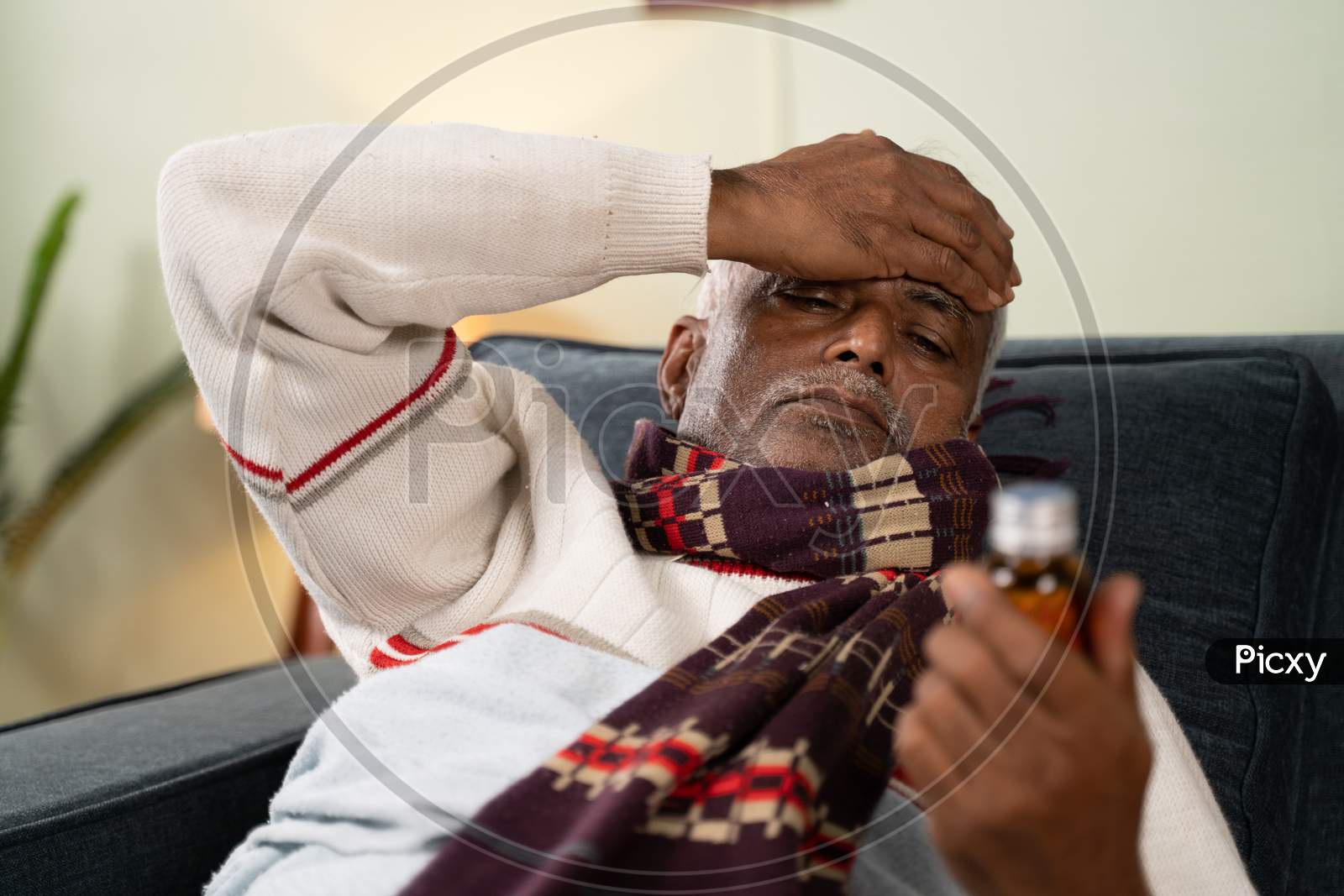 Sick Old Man Worried About Taking Pills By Placing Hand On His Head While Sleeping On Sofa Ta Home - Concept Of Senior People Worried About Pills Side Effects.