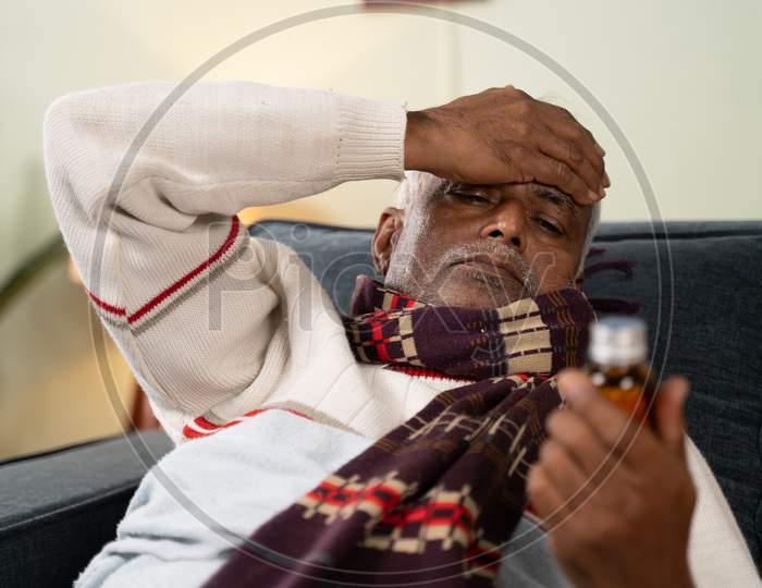 Sick Old Man Worried About Taking Pills By Placing Hand On His Head While Sleeping On Sofa Ta Home - Concept Of Senior People Worried About Pills Side Effects.