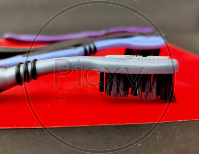 Turn Around Of Grey Tooth Brush With Black Bristle On Red Background